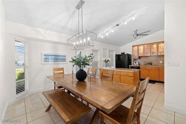 tiled dining area featuring sink, ceiling fan with notable chandelier, and vaulted ceiling