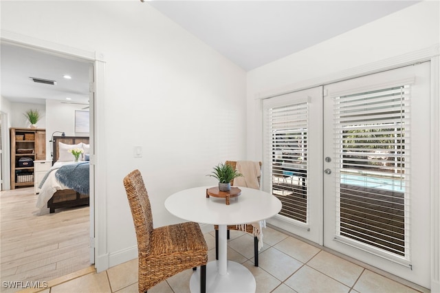 dining space with french doors, light wood-type flooring, and lofted ceiling