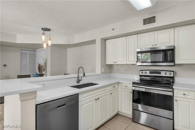 kitchen featuring sink, hanging light fixtures, light tile patterned floors, kitchen peninsula, and stainless steel appliances