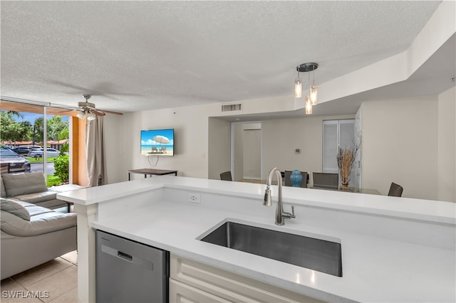 kitchen featuring a textured ceiling, sink, pendant lighting, dishwasher, and light tile patterned flooring