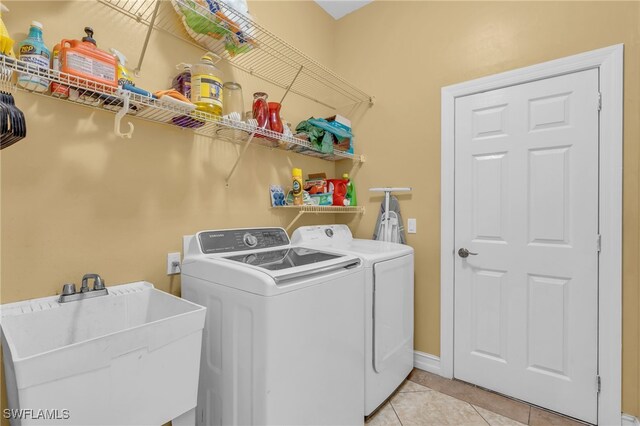 laundry room with light tile patterned floors, sink, and washing machine and clothes dryer