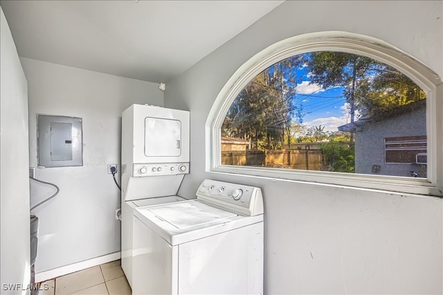 laundry room featuring light tile patterned floors, stacked washer / dryer, and electric panel