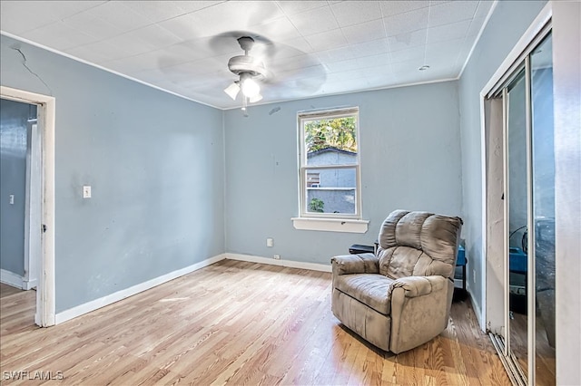 sitting room featuring ceiling fan, light wood-type flooring, and ornamental molding