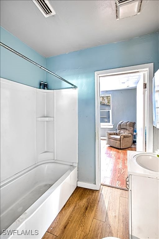 bathroom featuring vanity, wood-type flooring, and shower / washtub combination