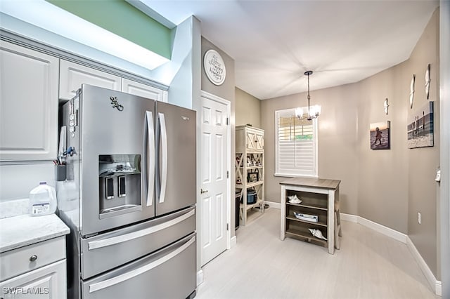 kitchen with white cabinets, hanging light fixtures, stainless steel fridge, light wood-type flooring, and a chandelier