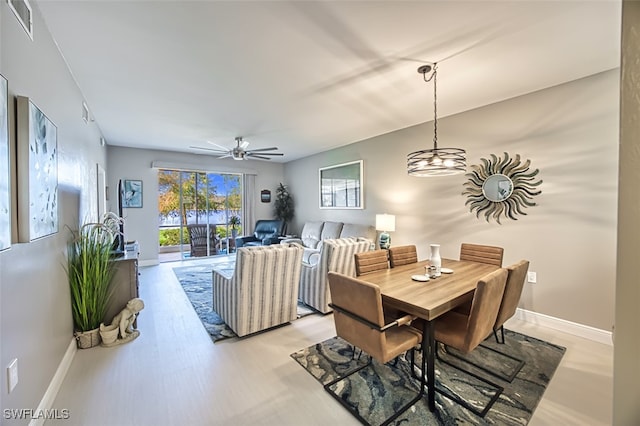 dining room featuring ceiling fan with notable chandelier and light hardwood / wood-style flooring