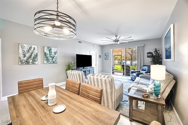 dining space with ceiling fan with notable chandelier