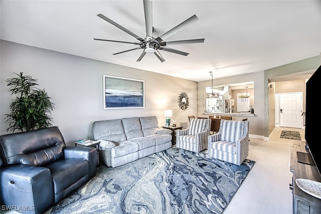 living room with ceiling fan with notable chandelier and hardwood / wood-style flooring