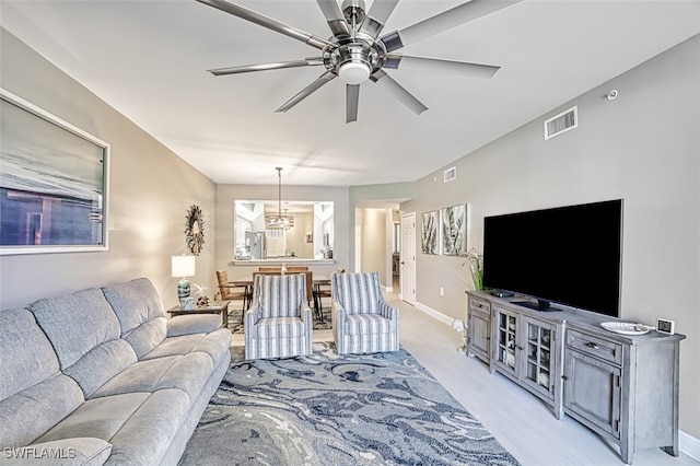 living room with ceiling fan with notable chandelier