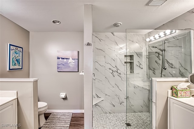 bathroom with tiled shower, vanity, hardwood / wood-style flooring, and toilet