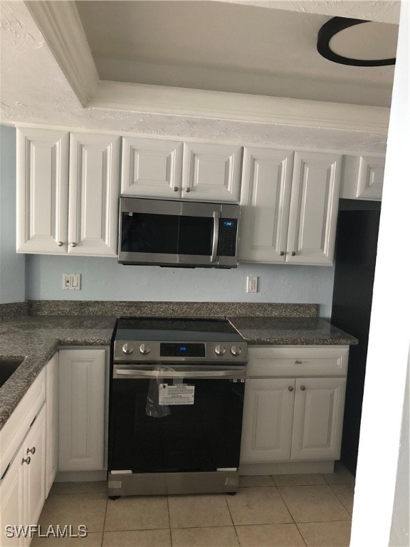 kitchen with white cabinetry, light tile patterned floors, and stainless steel appliances