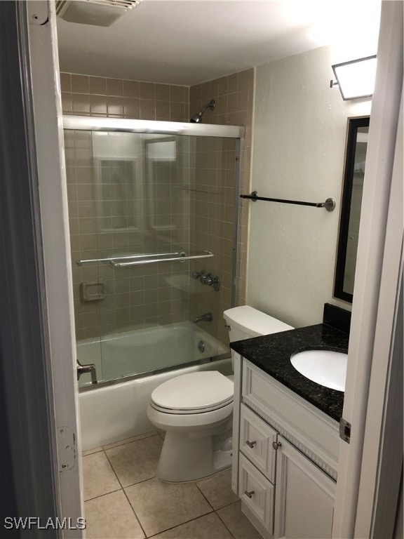 full bathroom featuring combined bath / shower with glass door, vanity, tile patterned floors, and toilet