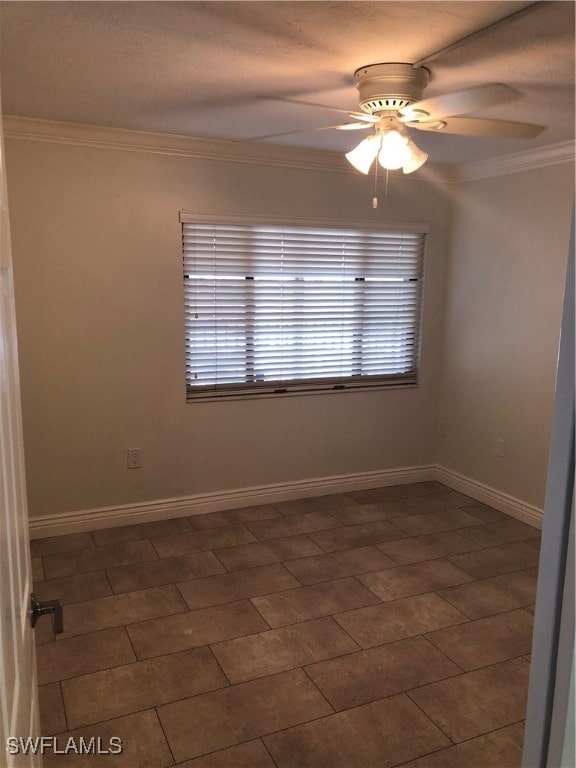 spare room featuring ceiling fan, dark tile patterned floors, a healthy amount of sunlight, and ornamental molding