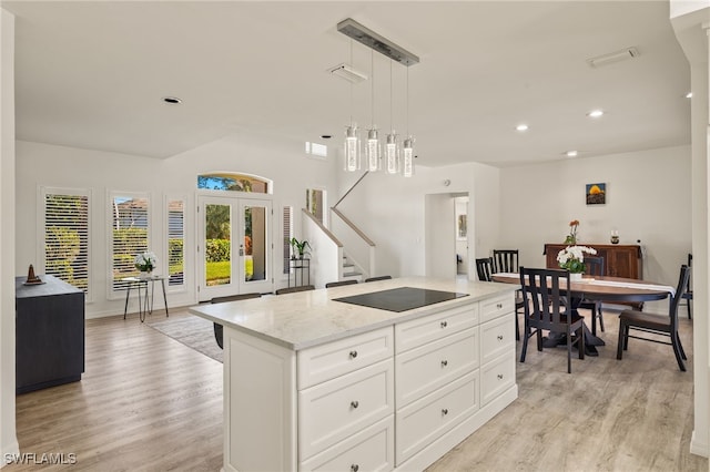 kitchen featuring white cabinets, a center island, light wood-type flooring, and hanging light fixtures