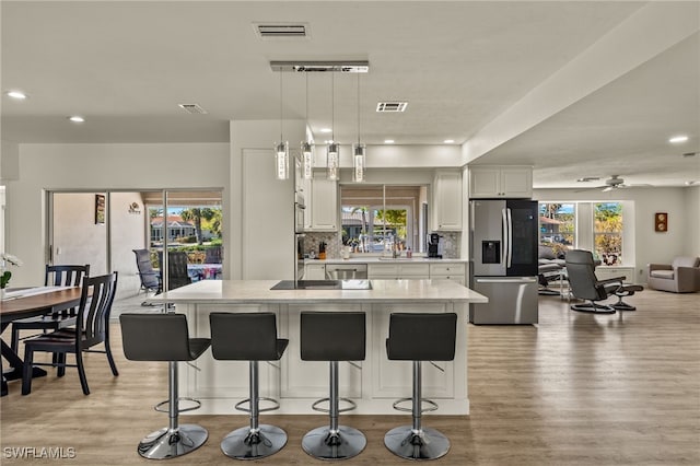 kitchen with a kitchen bar, stainless steel fridge with ice dispenser, a kitchen island, and hanging light fixtures