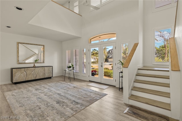 entrance foyer featuring a towering ceiling, french doors, light wood-type flooring, and plenty of natural light