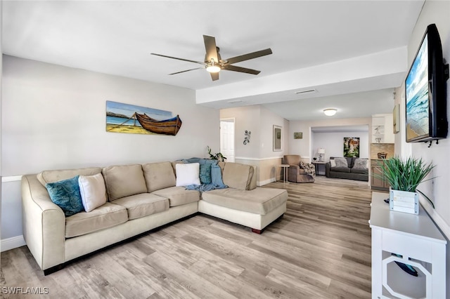 living room featuring light wood-style floors, visible vents, baseboards, and a ceiling fan