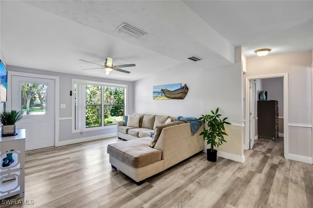 living room with light wood-style flooring, visible vents, ceiling fan, and baseboards