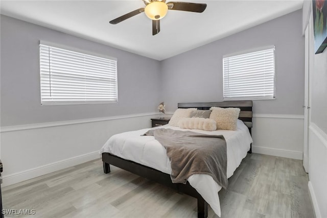 bedroom featuring light wood-style floors, multiple windows, and baseboards