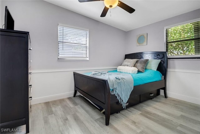 bedroom with ceiling fan, wood finished floors, and baseboards