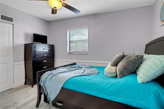 bedroom featuring wood finished floors, visible vents, and a ceiling fan