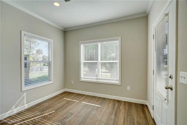 empty room with hardwood / wood-style floors and crown molding