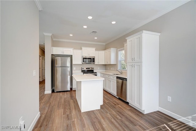 kitchen featuring appliances with stainless steel finishes, a center island, light hardwood / wood-style flooring, and white cabinetry