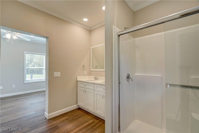 bathroom with ornamental molding, vanity, a shower with door, ceiling fan, and wood-type flooring