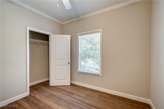 unfurnished bedroom with a closet, ceiling fan, hardwood / wood-style floors, and crown molding