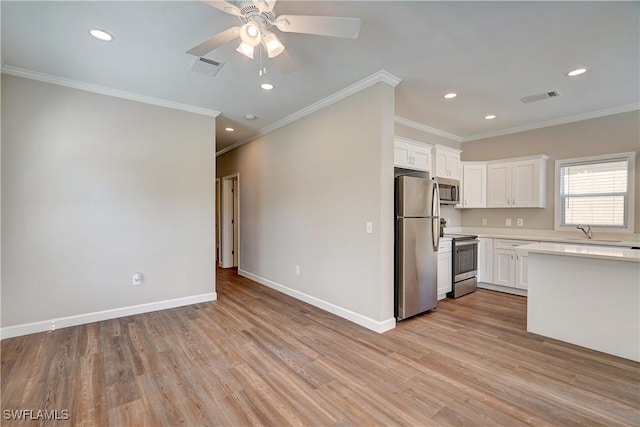 kitchen with appliances with stainless steel finishes, light hardwood / wood-style flooring, white cabinetry, and ornamental molding