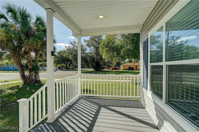 wooden terrace featuring a lawn and a porch