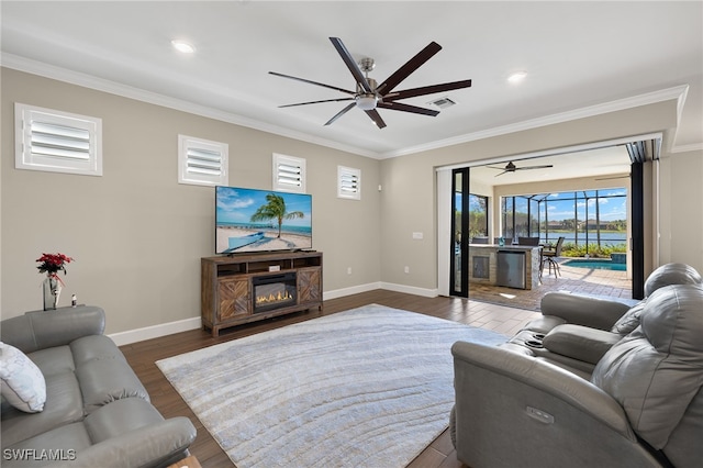 living room with dark hardwood / wood-style floors, a fireplace, crown molding, and ceiling fan