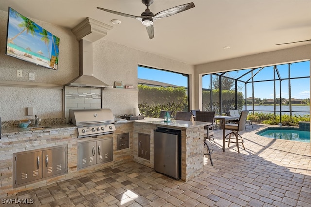 view of patio / terrace featuring an outdoor kitchen, a water view, an outdoor wet bar, a lanai, and area for grilling