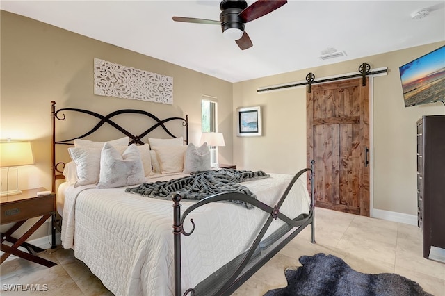 tiled bedroom featuring ceiling fan and a barn door