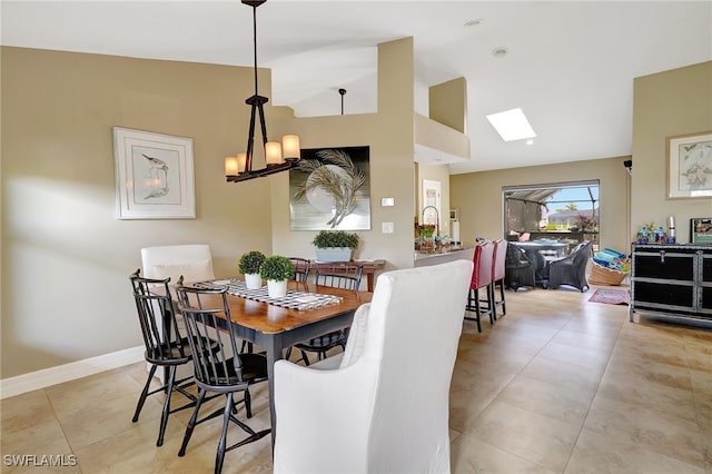 dining area with vaulted ceiling with skylight, light tile patterned floors, and a notable chandelier