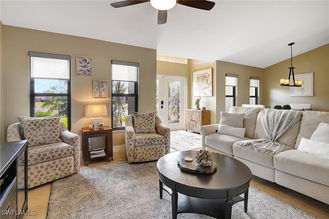 living room with ceiling fan with notable chandelier, a wealth of natural light, and lofted ceiling