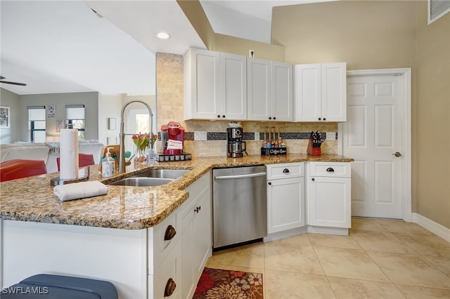 kitchen with kitchen peninsula, light stone countertops, stainless steel dishwasher, sink, and white cabinetry