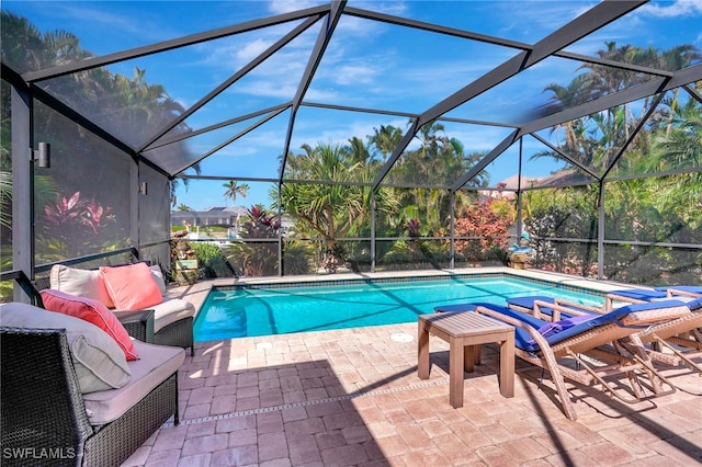 view of pool featuring a patio, glass enclosure, and an outdoor hangout area