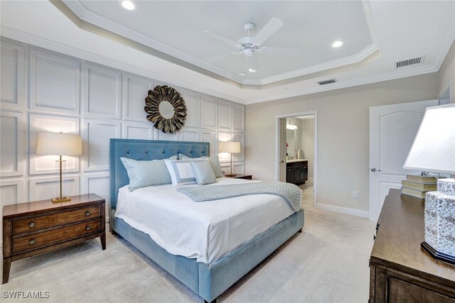 bedroom featuring ensuite bathroom, ornamental molding, light colored carpet, a raised ceiling, and ceiling fan