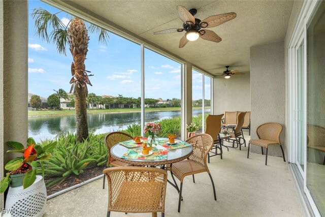 sunroom / solarium featuring ceiling fan and a water view