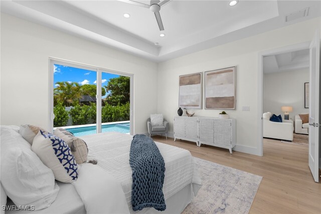 bedroom with access to outside, ceiling fan, light hardwood / wood-style floors, and a tray ceiling