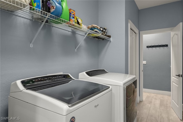 laundry area with separate washer and dryer and light wood-type flooring