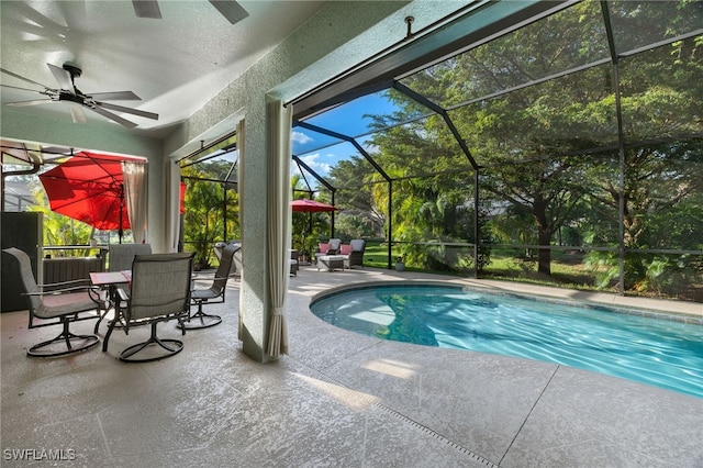 view of swimming pool with glass enclosure, ceiling fan, and a patio area