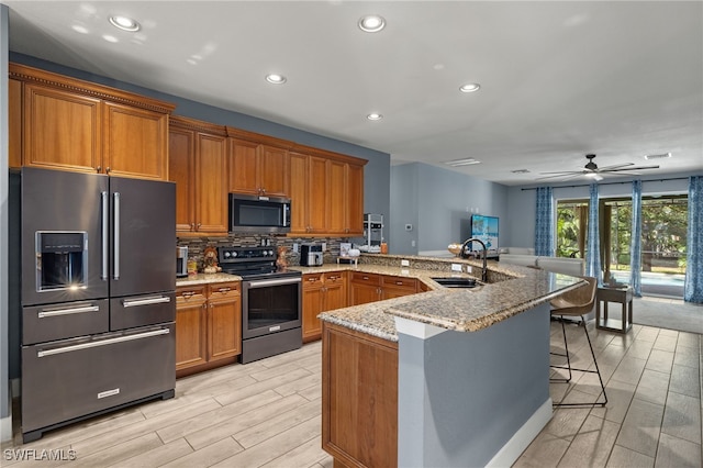 kitchen featuring sink, a breakfast bar area, ceiling fan, kitchen peninsula, and stainless steel appliances