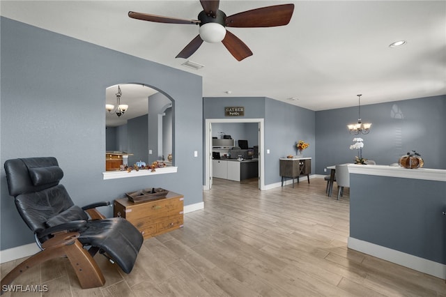 sitting room featuring ceiling fan with notable chandelier and light wood-type flooring