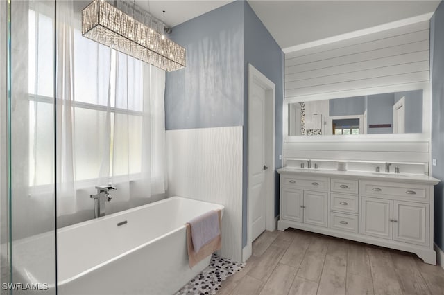 bathroom with hardwood / wood-style floors, a bathtub, vanity, and an inviting chandelier