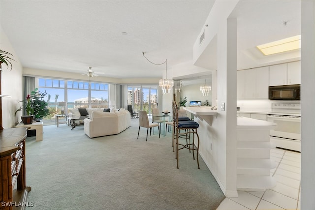 carpeted living room featuring a skylight and ceiling fan with notable chandelier