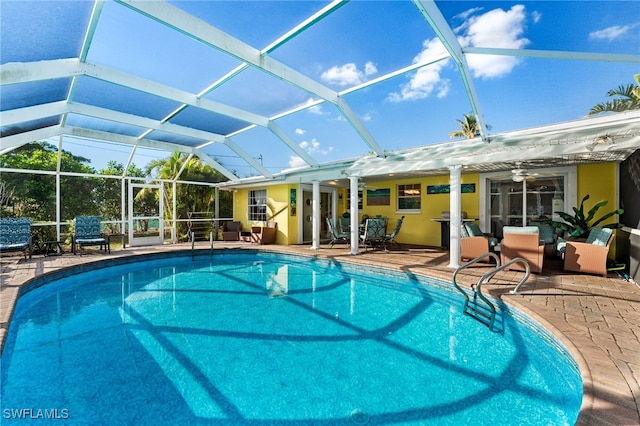 view of swimming pool featuring ceiling fan, a patio area, and glass enclosure