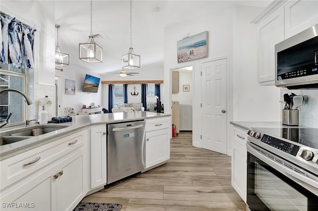 kitchen with white cabinets, hanging light fixtures, sink, decorative backsplash, and appliances with stainless steel finishes