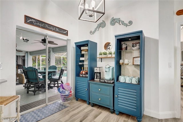 interior space featuring ceiling fan with notable chandelier, light wood-type flooring, and blue cabinets